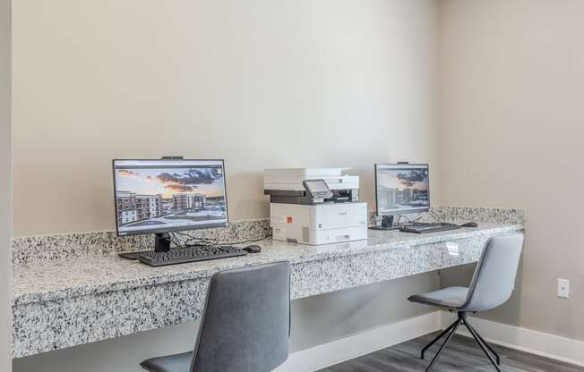 a office with two computers and a printer on a desk