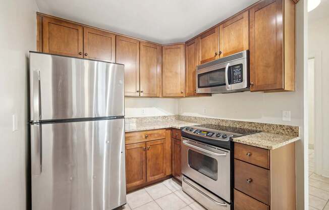 A kitchen with a stainless steel refrigerator, microwave, oven, and cabinets.