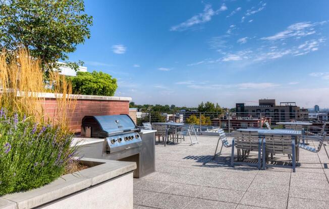 a barbecue grill on the roof of a building with tables and chairs