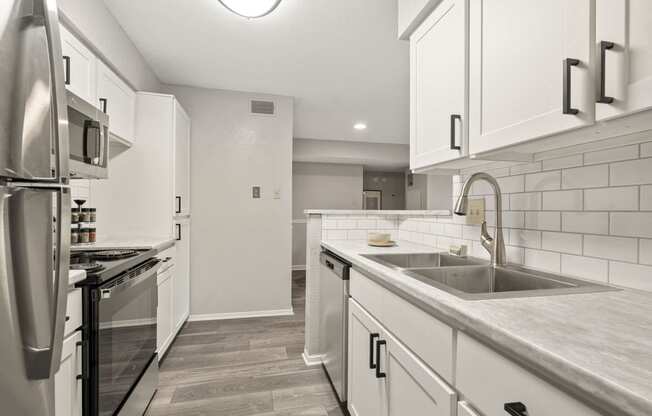 a renovated kitchen with white cabinets and stainless steel appliances