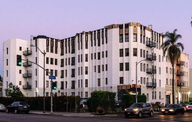 a white building on the corner of a street with cars driving in front of it