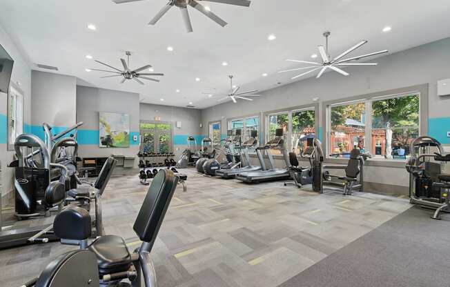 A spacious gym with a variety of exercise equipment and a ceiling fan.
