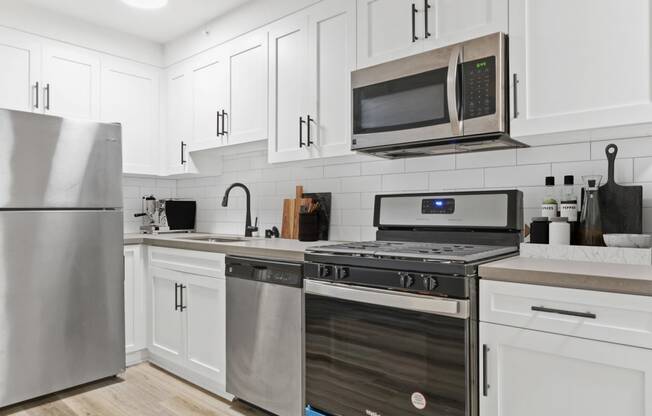 a white kitchen with stainless steel appliances and white cabinets