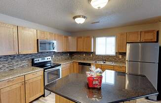 apartment kitchen with a granite counter top and wooden cabinets