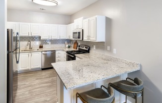 a kitchen with white cabinets and a marble counter top