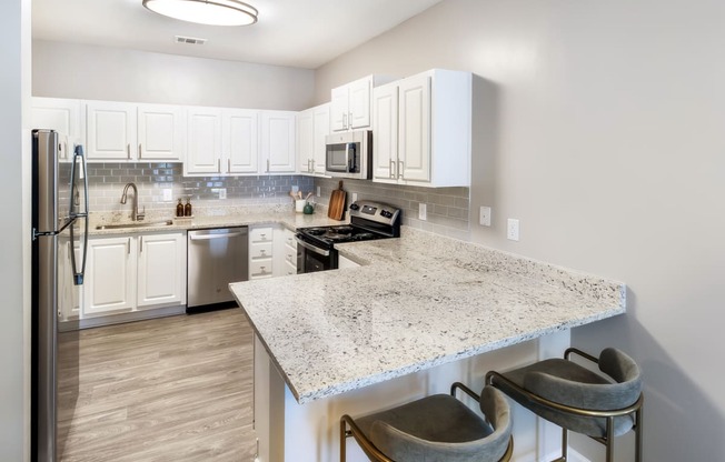 a kitchen with white cabinets and a marble counter top