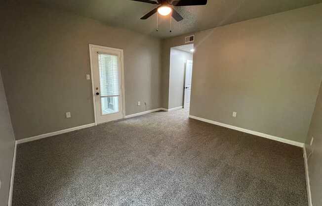 A room with a ceiling fan and carpeted floor.