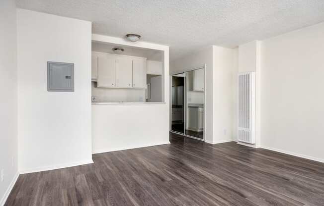 an empty living room and kitchen with white walls and wood flooring