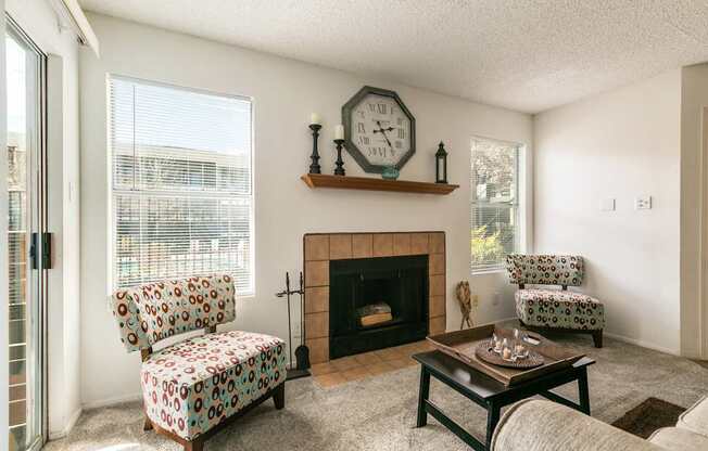 A living room with a fireplace, two chairs, and a clock on the wall.