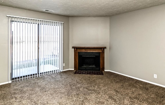 an empty living room with a fireplace and a sliding glass door