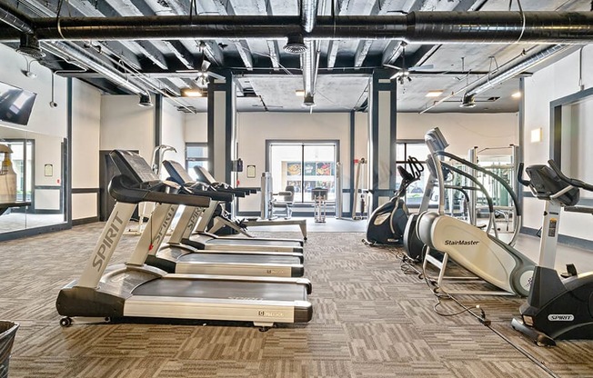 a gym with cardio equipment and weights on the floor