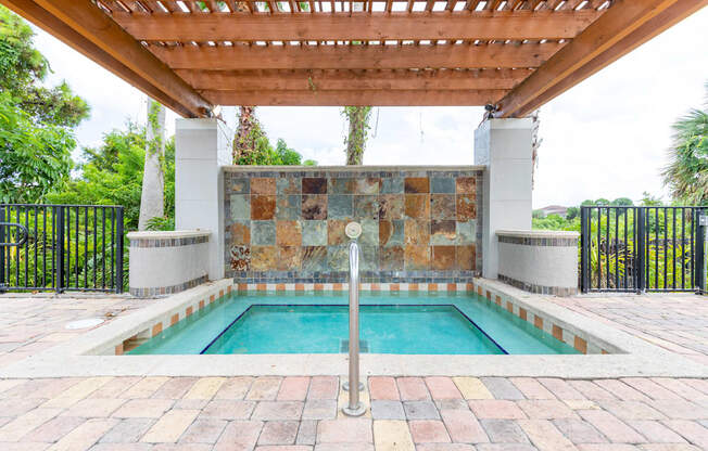 a swimming pool with a stone wall and a wooden pergola at Heritage Bay, Florida