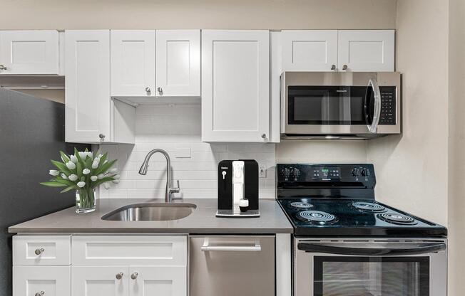 a kitchen with white cabinets and a stove and a microwave