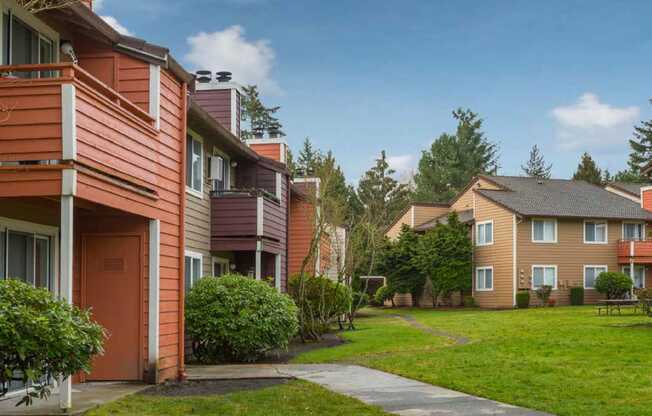 a walkway between two apartment buildings with grass and trees at Quartz Creek, Mountlake Terrace, WA, 98043