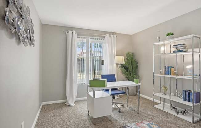 a living room with a desk and a window and a closet