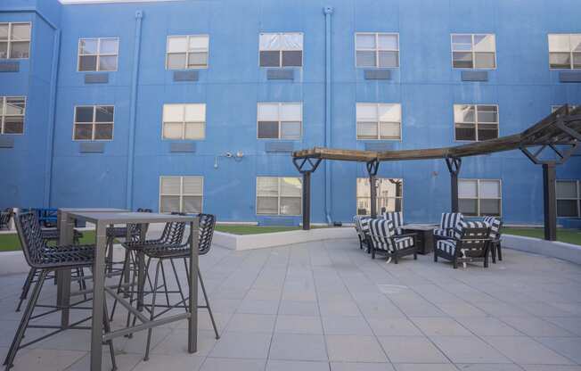 a patio with tables and chairs in front of a blue building