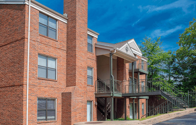 a brick apartment building with a balcony and a blue sky