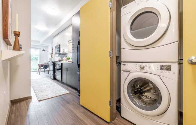 In Unit Laundry with Dryer Stacked On Top of Washer, Yellow Door and Hardwood Inspired Floors