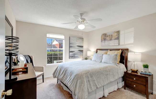 A bedroom with a large bed, a dresser, and a ceiling fan.