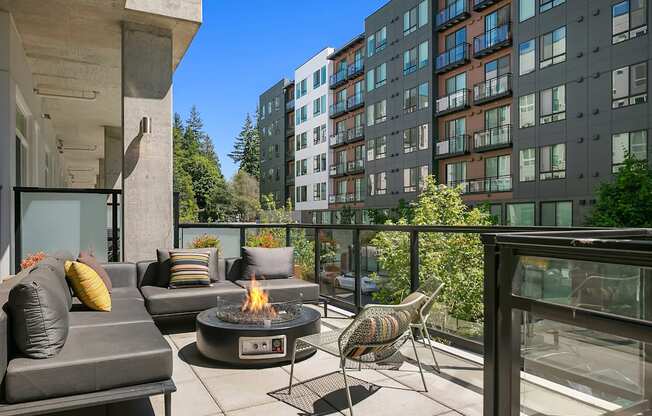 A patio with a fire pit and chairs.