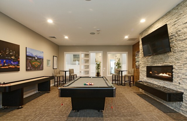 Game room with billiards table, flat screen television, fireplace, shuffleboard, and seating areas