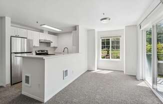 A kitchen with white cabinets and a stainless steel refrigerator.