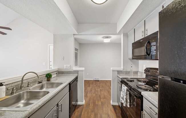 A kitchen with a stainless steel sink and black appliances.