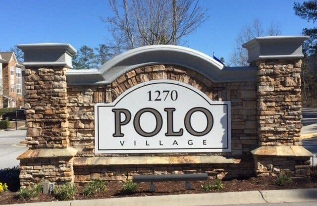 a sign for polo village on the side of a street
