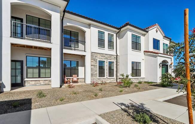 an exterior view of three buildings with a sidewalk in front of them at Stella, San Tan Valley, AZ