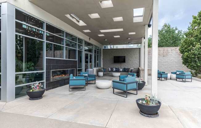 an outdoor patio with blue chairs and a fireplace