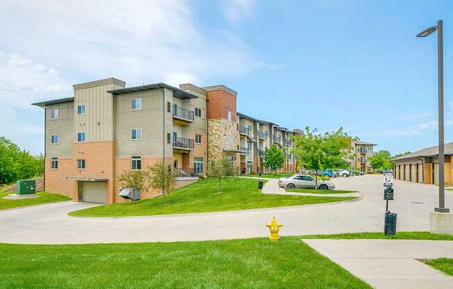 The side of a brick apartment building with green lawns, and a drive leading to an underground parking garage.