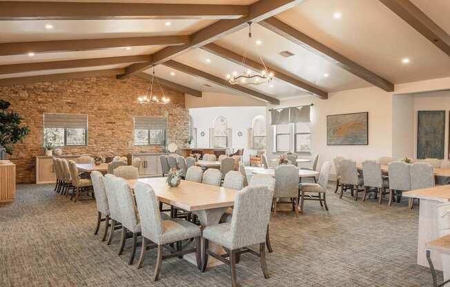 A room with tables and chairs and a stone wall.
