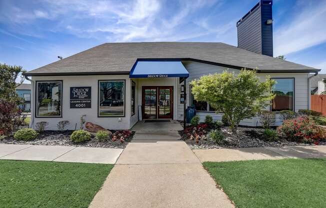 the front of a white building with a sidewalk and lawn