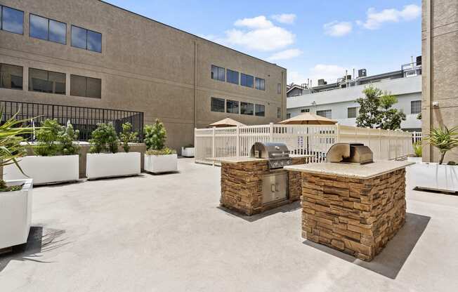 North Hollywood Apartments - Community Sun Deck with Two BBQ Grills with Built In Counters and Surrounded by Potted Greenery.