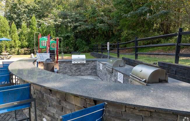 A playground with a slide and a play area with a wall and a trash can.