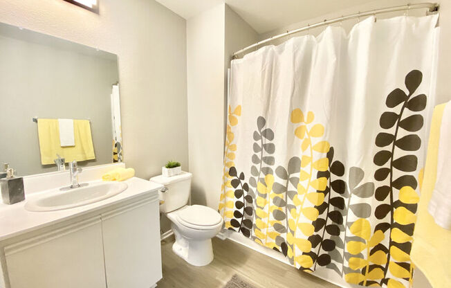 a bathroom with a shower curtain and a sink and a toilet at BLVD Apartments LLC, Tarzana, CA 91356