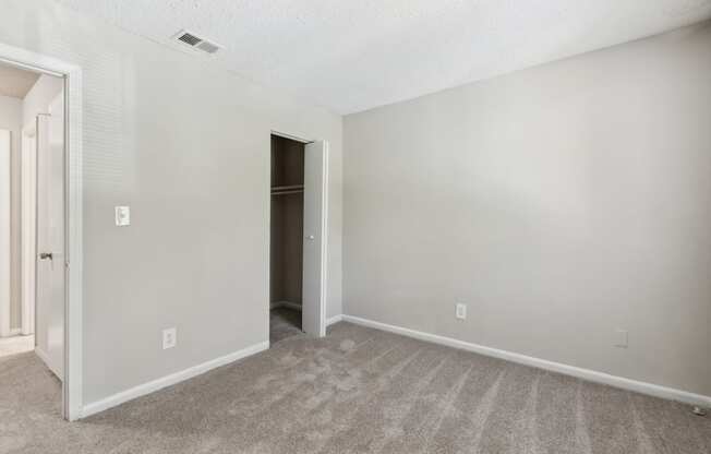 an empty living room with carpet and a door to a closet