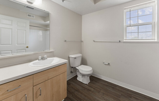 a bathroom with a window, toilet and a sink and a mirror  at Hunters Pond Apartment Homes, Illinois, 61820