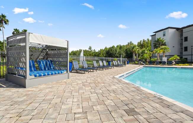 A poolside area with a sunshade, lounge chairs, and a pool.