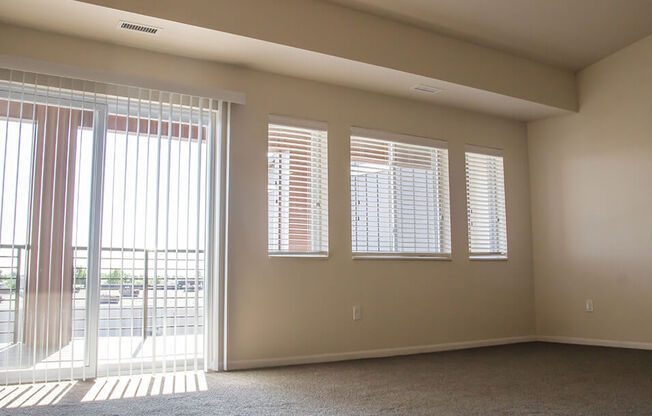 an empty room with a sliding glass door and four windows