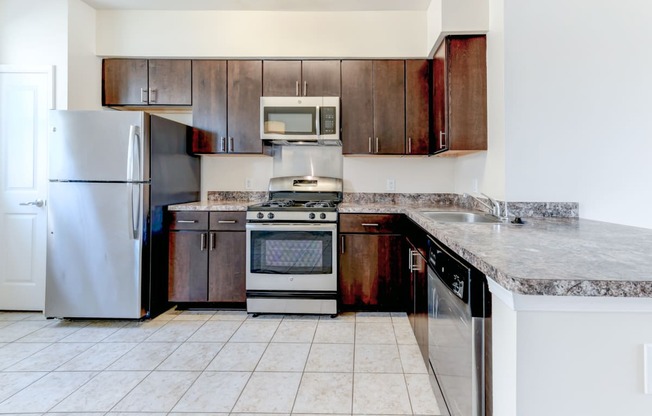 kitchen with espresso cabinetry, breakfast bar and stainless steel appliances at sheridan station south townhomes in washington dc