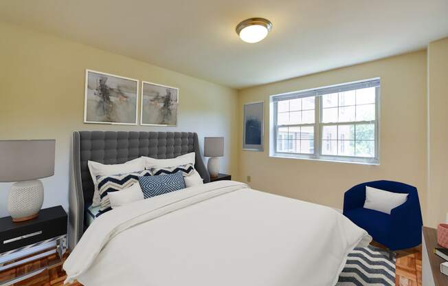 bedroom with bed, nightstands, parquet flooring and large window at shipley park apartments in washington dc