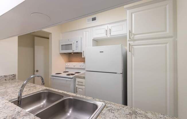 Kitchen with white cabinets and white appliances in a 2 bedroom, 1.5 bath 846 sq ft apartment home at The Biltmore Apartments located in the Vickery Midtown neighborhood of Dallas, TX.