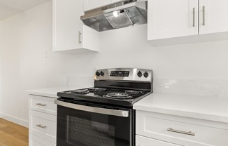 A modern kitchen with a stove top oven and white cabinets.