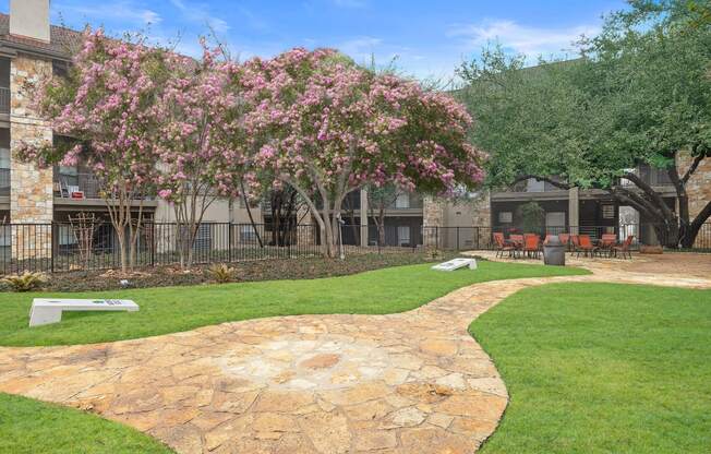 a courtyard with a stone path and a pink flowering tree