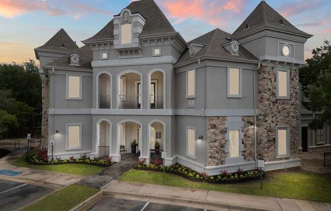 A large, grey mansion with a tower and arched doorways.