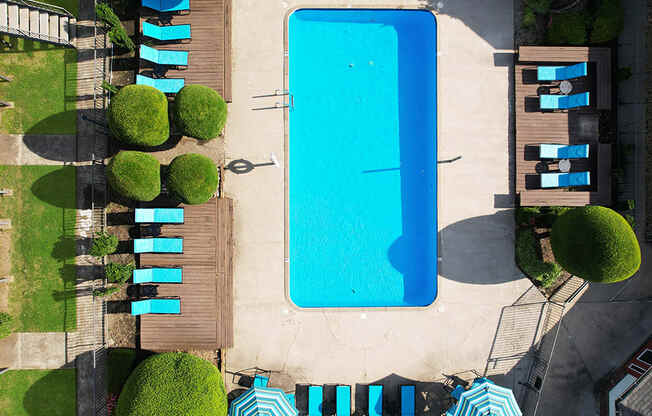 an aerial view of a swimming pool with umbrellas and chairs around it