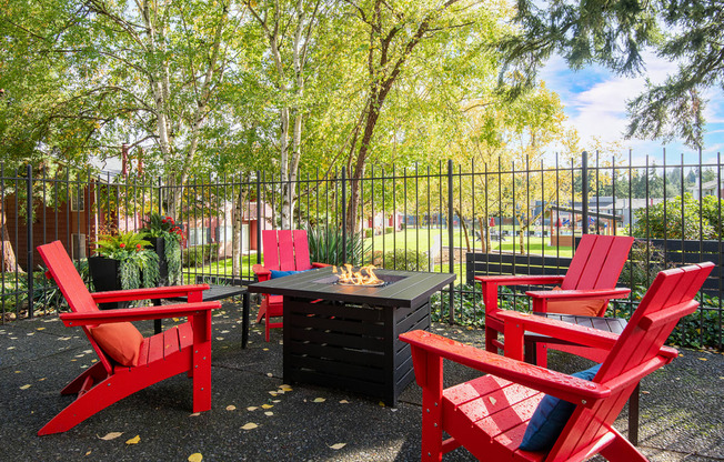 a patio with red chairs and a table and a fire pit