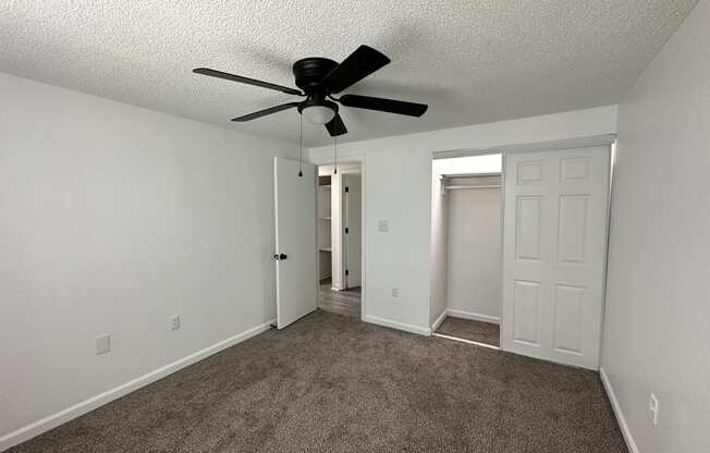 an empty bedroom with a ceiling fan