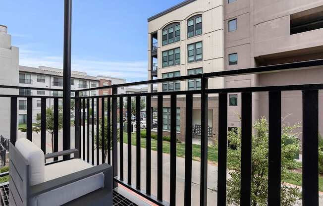 A balcony with a black railing and a white chair.